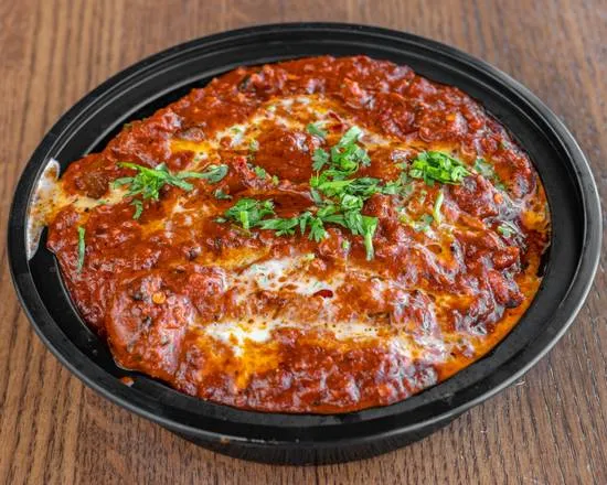 Butter chicken in a rich tomato and cream sauce topped with fresh coriander, packed for takeout at Shehnai Restaurant, Hamilton